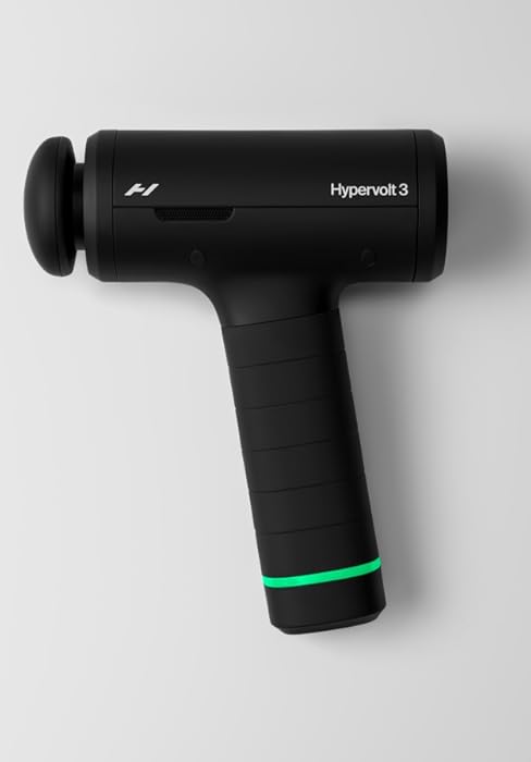 Black handheld massage gun device with cylindrical shape, featuring a green accent ring near the ergonomic grip. Professional-style percussion therapy tool.