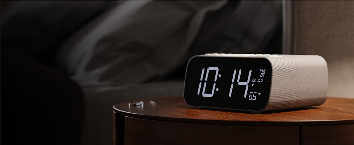 Bedside digital alarm clock shows 1014 PM and 66°F on a wooden table, soft ambient lighting, sleek