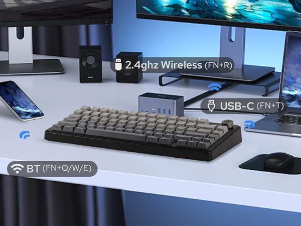 a desk with a keyboard, mouse, speakers, and other electronics.