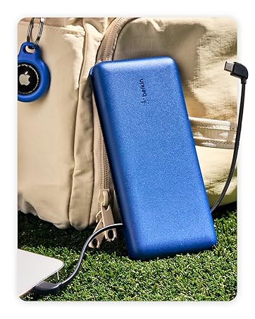 Image of belkin portable charger power bank next to backpack and phone on grass.