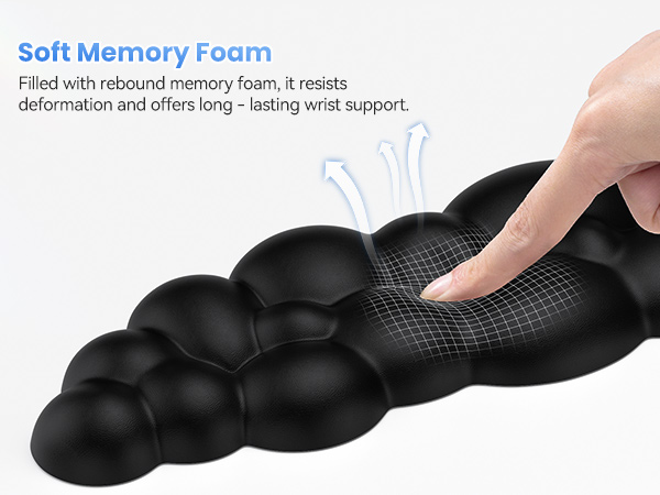 Black ergonomic wrist rest with soft memory foam, demonstrating its rebound properties. Features a textured surface and bubble-like design for long-lasting support.