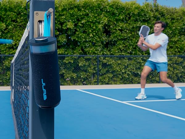 Go party speaker hanging on its carrying strap on a pickelball court divider