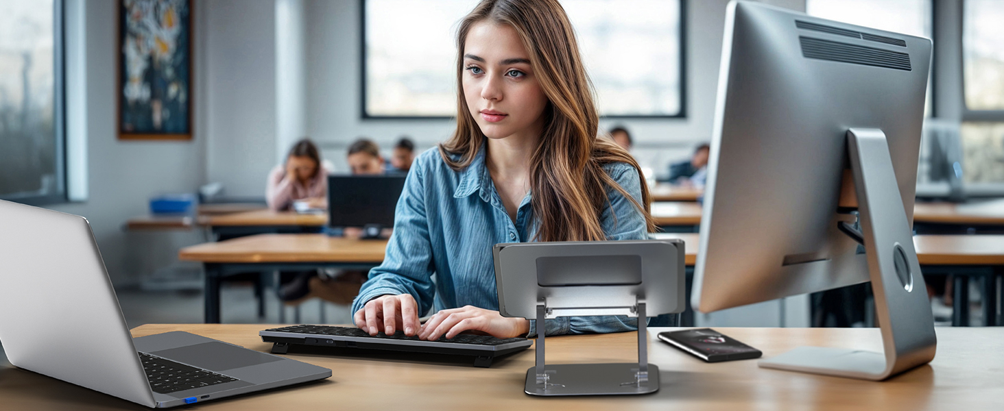 Office workspace with desktop computer, laptop, and electronic devices arranged on desk in modern office environment with natural lighting.