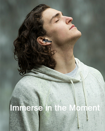 Modern wireless earbud shown being worn, with text 'Immerse in the Moment' overlaid on lifestyle photo featuring light gray hoodie.