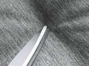 Close-up of a silver-colored metal edge or tool against a textured gray fabric or surface.