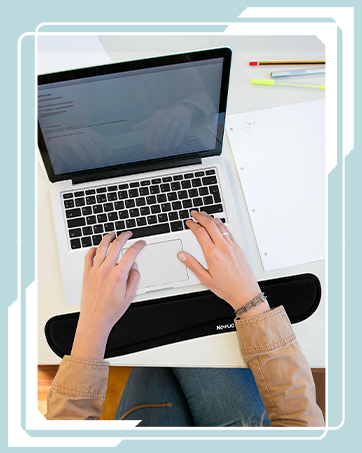 Person using a laptop computer, hands on keyboard. Workspace setup with notebook and writing tools visible nearby.