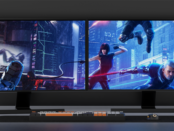Ultrawide gaming monitor displaying a futuristic action scene. Below, a keyboard with orange backlit keys and additional controls is visible.