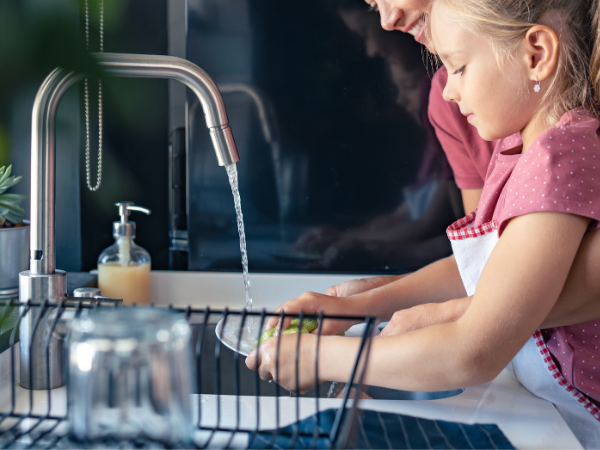 woman and child cleaning dishes together at the sink