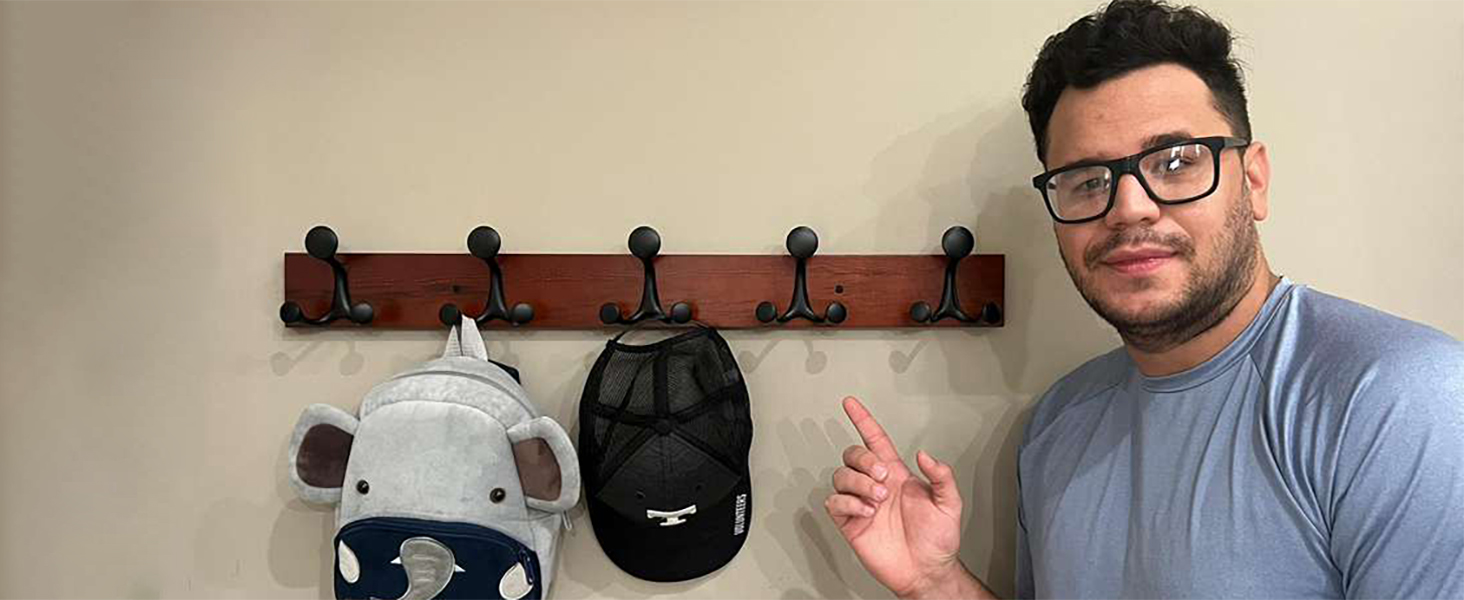 A man is very happy that this coat rack holds his backpack and hat.