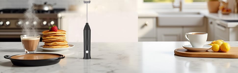 Black milk Frother on a Kitchen Counter next to a cup of cofee and plates of panckaes