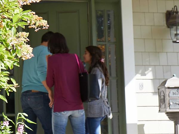 Family entering front door of home, push button doorbell installed to side of door