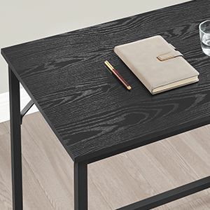 a black and wood desk with a notebook and a glass of water on top.