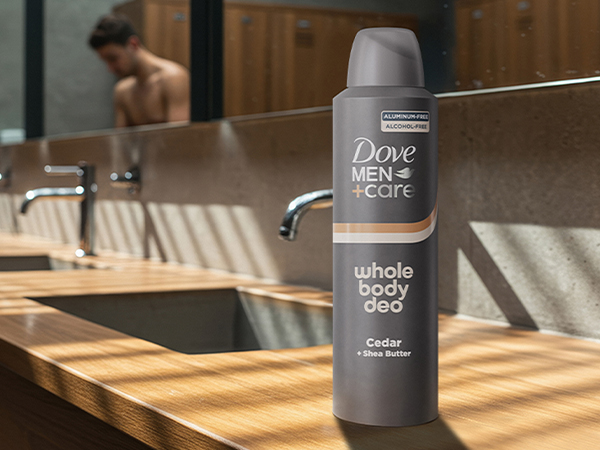 Man using sink in locker room; Dove Men+Care deodorant on counter