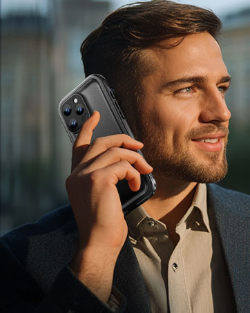 Dark gray smartphone with triple camera system being held up during a call, showcasing its sleek profile against natural lighting.