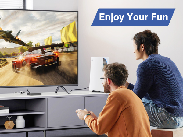 Text reads 'Enjoy Your Fun'. Gaming scene showing two people sitting on couch playing video game on TV displaying racing game graphics.
