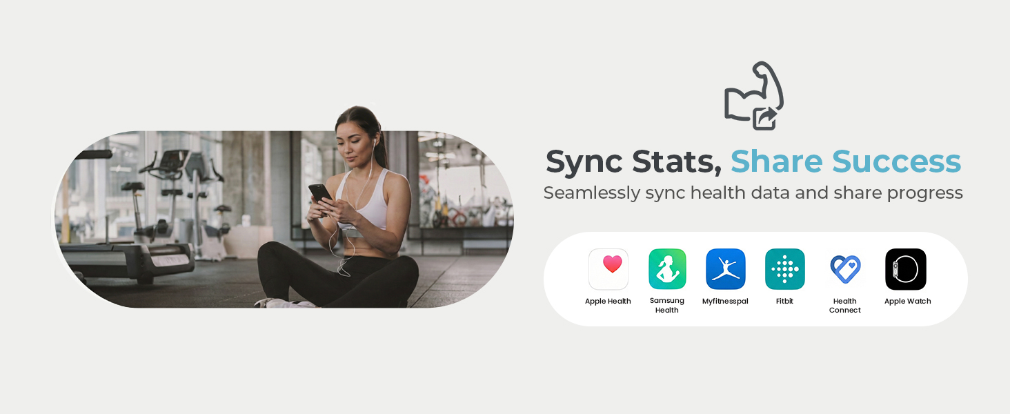 A woman sits cross-legged on the gym floor, checking her phone to share progress.