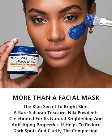 Model applies blue clay mask holding Argaviva Nila & Vitamin C Clay Face Mask jar