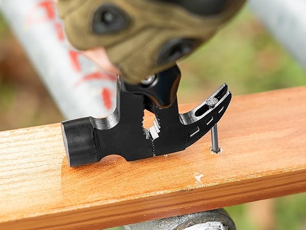 Close-up of a small black clip or fastener attached to wooden surface, with partial view of white and red object.