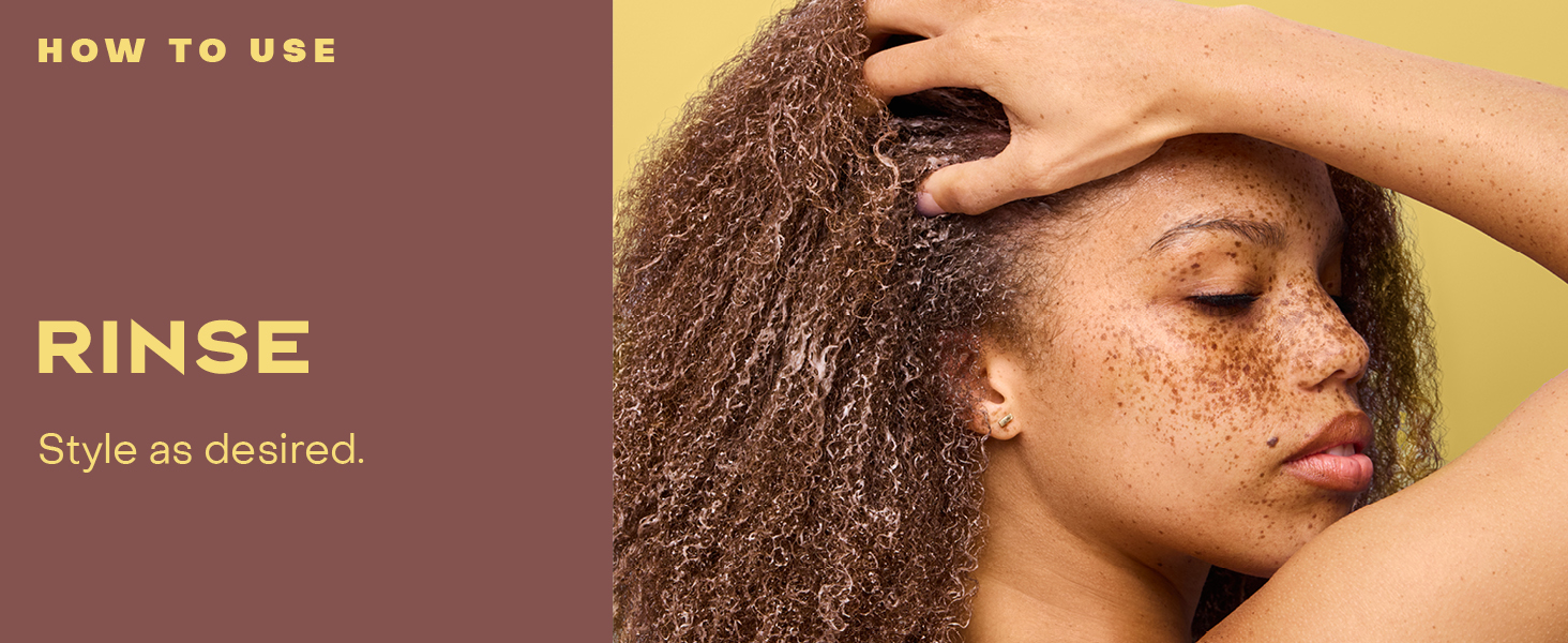 Image of a woman with curly hair rinsing it.