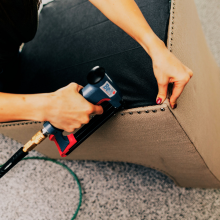 Cambric dust cover being stapled to bottom of chair during upholstery for clean professional finish