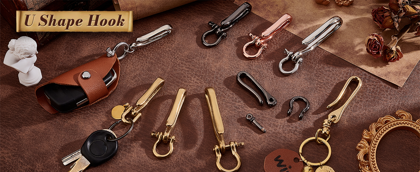 Assortment of U-shaped metal hooks and carabiners in various sizes and finishes. Displayed on a textured brown surface with leather keychain.