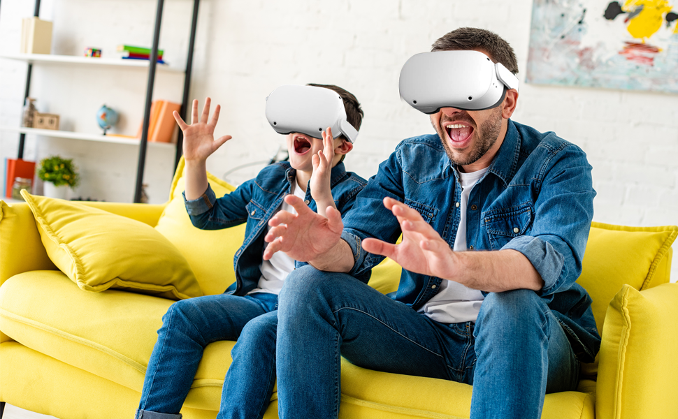 a man and a boy sitting on a couch wearing virtual reality goggles.