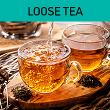 Pouring water into two clear glasses of tea on a wooden serving plate
