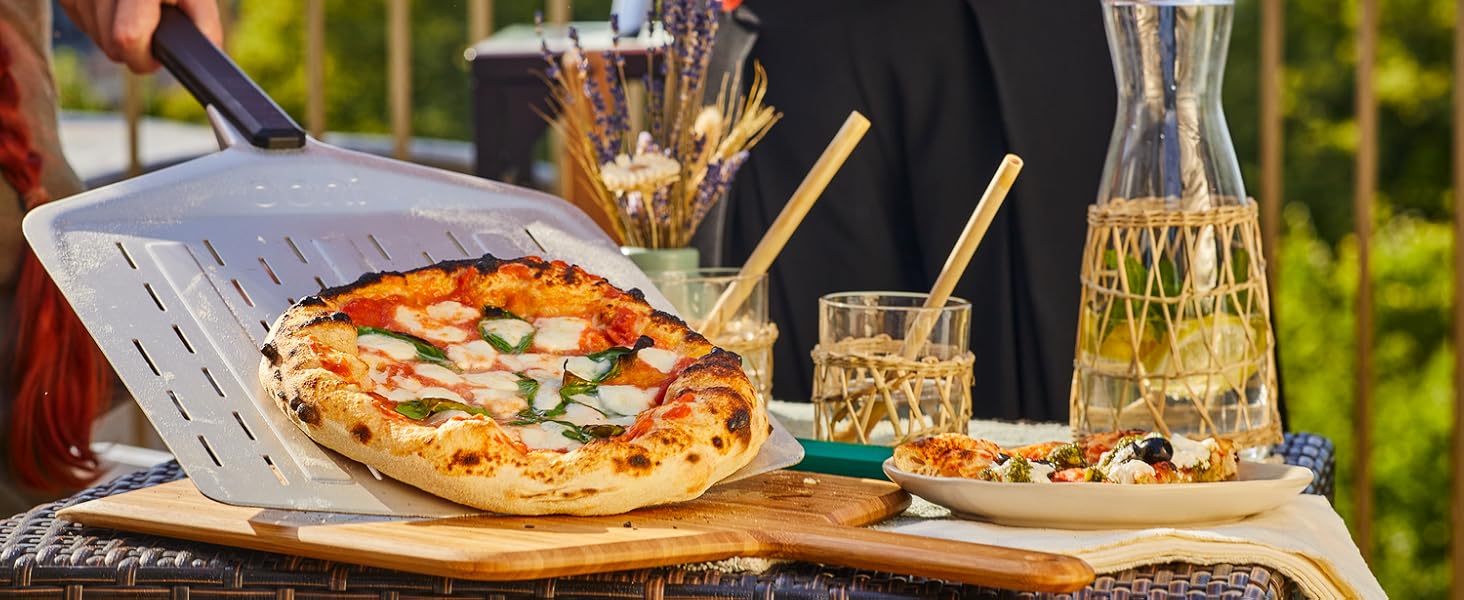 Outdoor pizza dining scene with hands serving a freshly baked pizza, alongside glasses and a carafe of water.