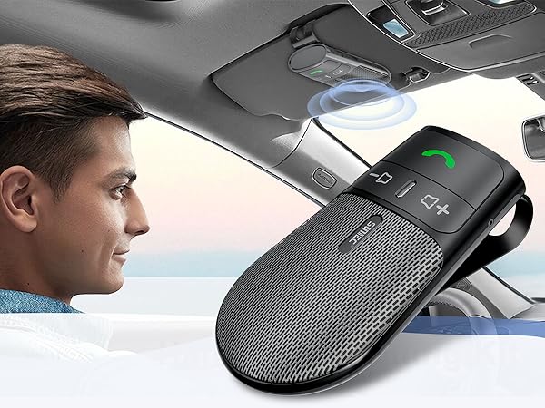 Black speakerphone device mounted on car visor, featuring mesh texture and control buttons.