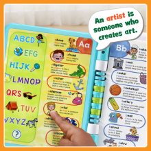 Hand touching one of the interactive pages; toy says “An artist is someone who creates art.”