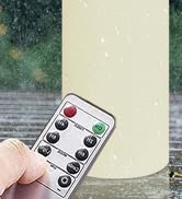 Hand holding a small white remote control with multiple buttons. The remote appears to be aimed towards an unseen device off-screen.
