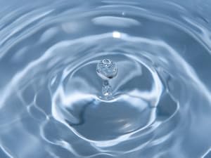 water droplet falling into a blue bowl.