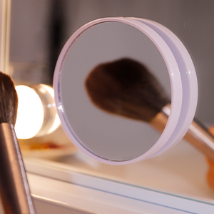 Close-up of a circular white magnifying mirror with LED lighting, positioned on a wooden surface.