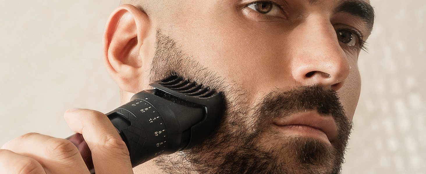 Black electric beard trimmer in use, shaping facial hair along jawline. Device has multiple length settings visible on its body.