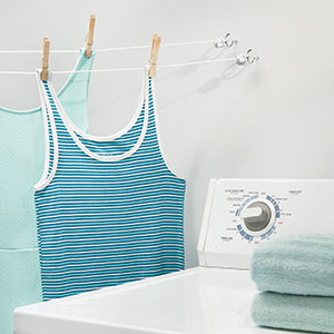 tank tops on clothes pins, wall mounted clothesline, side of white washing machine, towel on top