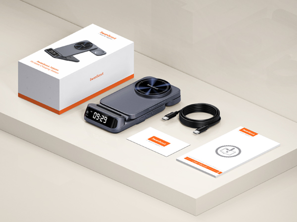 Flat black electronic device with circular fan, digital display showing time, accompanied by USB cable, user manual, and retail box on light surface.