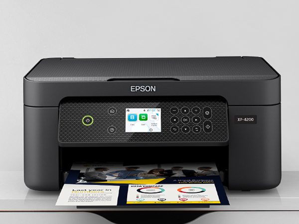 Black Expression Home XP-4200 sitting on cabinet with colorful business flyer in output tray. 