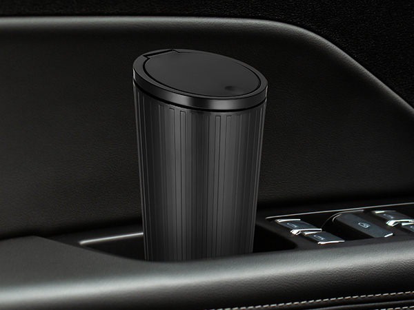 Black cylindrical car cup holder with vertical ridged texture and push-button lid, integrated into a dark vehicle interior armrest.