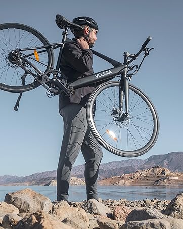 a man carrying a bike over a lake