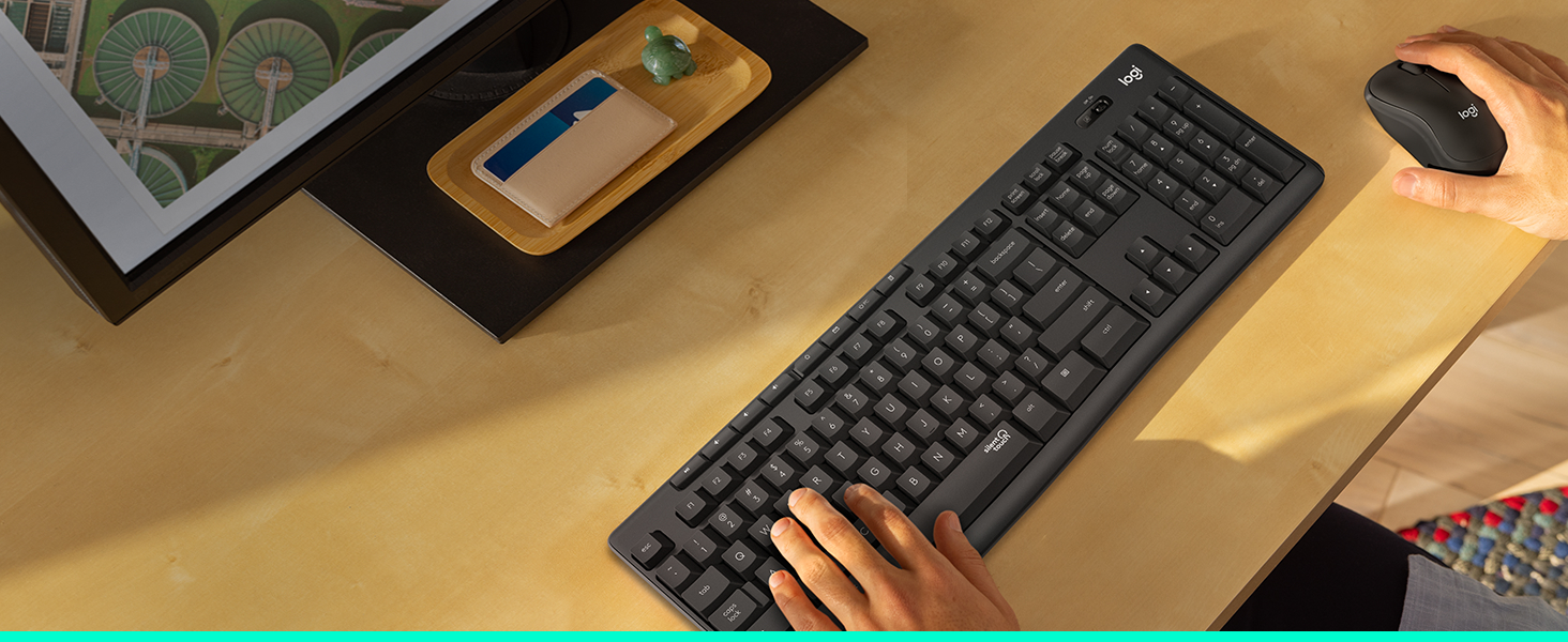 a man typing on the keyboard of mk295 wireless keyboard and mouse graphite combo