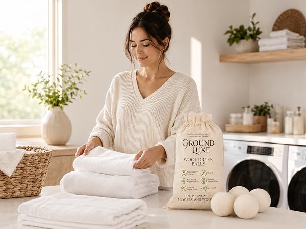 Woman folding soft towels with wool dryer balls in a bright laundry room