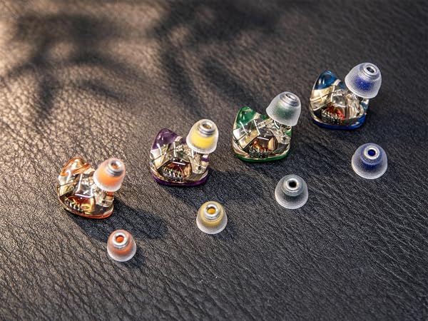 Collection of small decorative glass domes or cloches arranged on dark slate surface, varying in sizes with detailed miniature contents beneath.