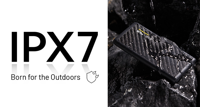 The NB Plus with water dripping down it while it sits against dark rocks.