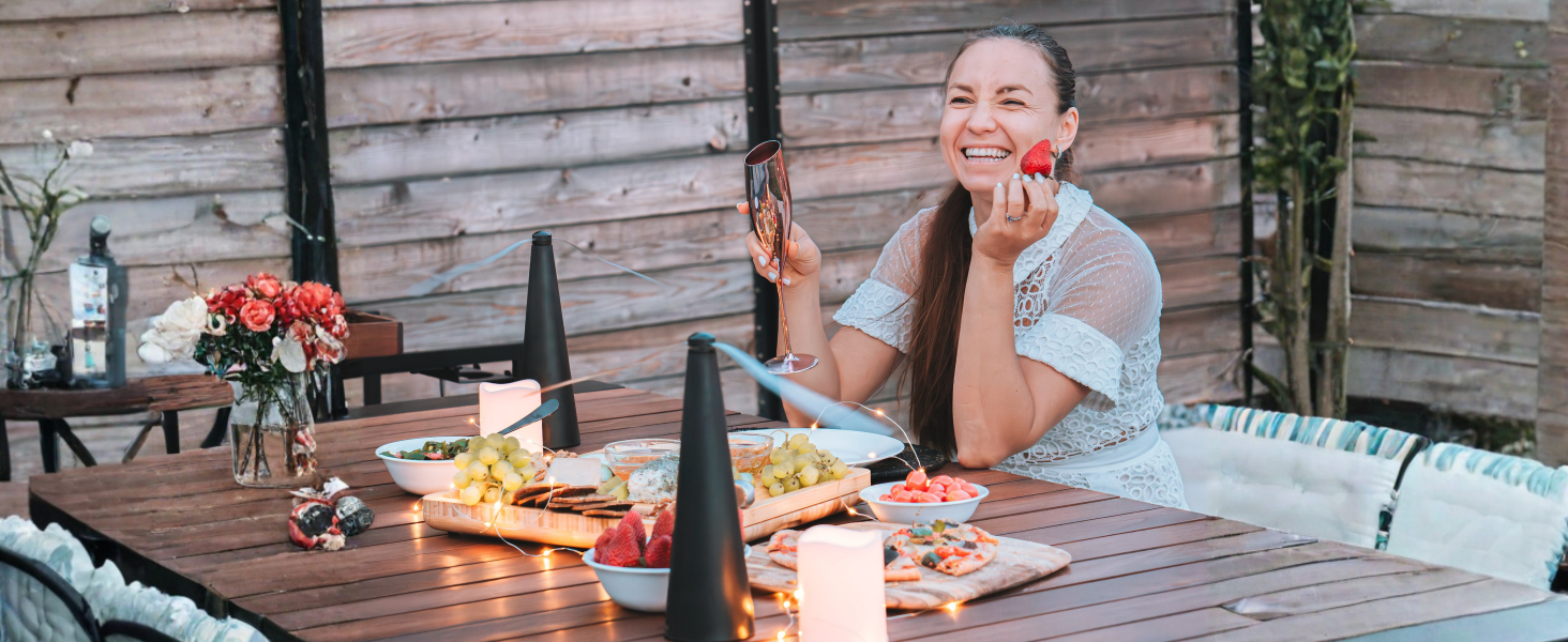 Woman enjoying outdoor dining with Fly Away fans keeping flies away from food on a patio table.