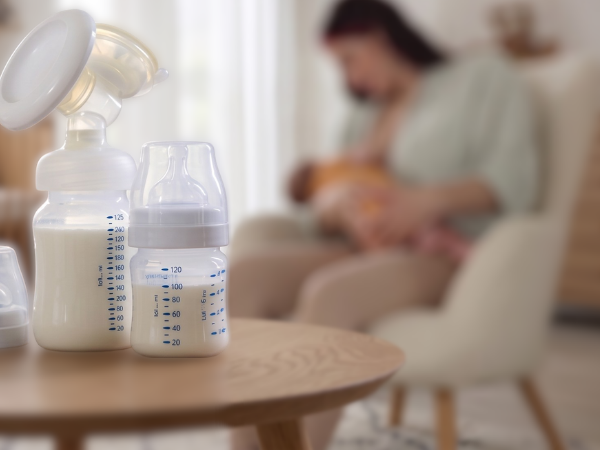 mother breastfeeding child with pump and bottles and breastmilk