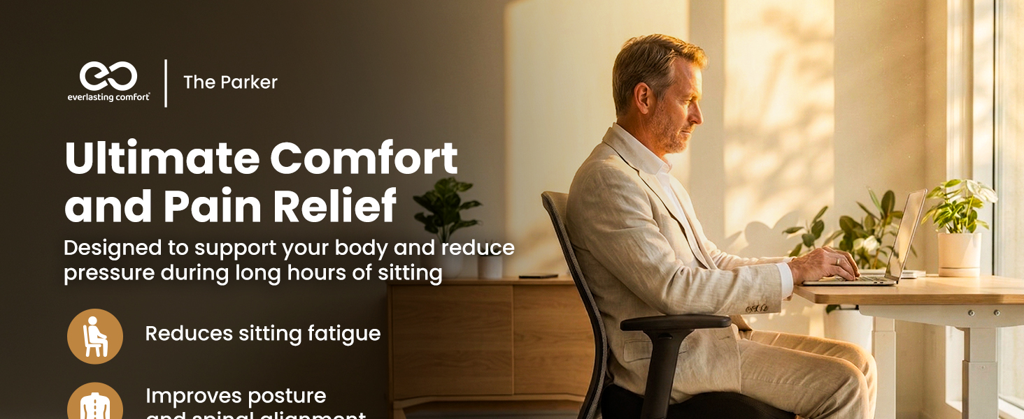 Man in business suit sits on an ergonomic office chair, working at his desk with a laptop.