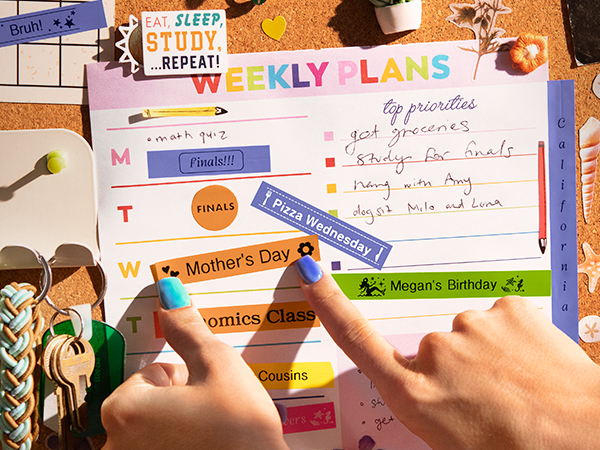 Person applying colorful Brother P-touch Btag reminder labels to calendar on form room cork board