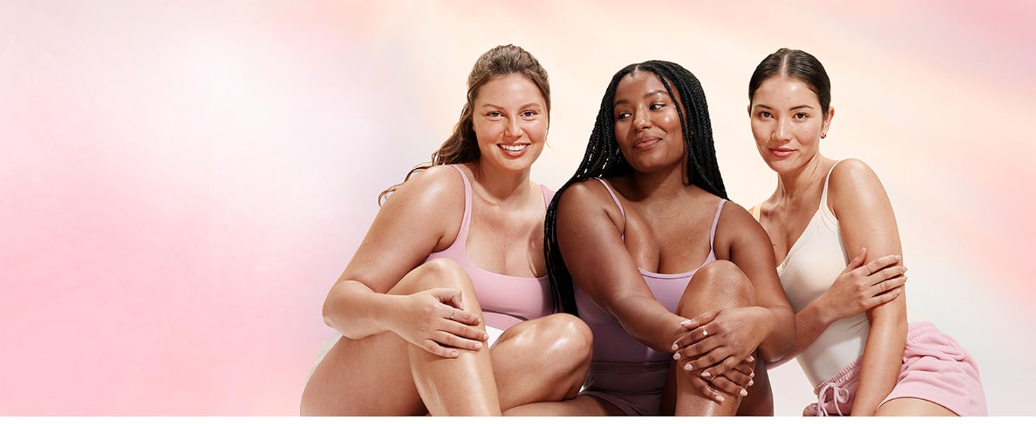 Three diverse women sitting in front of a pink background