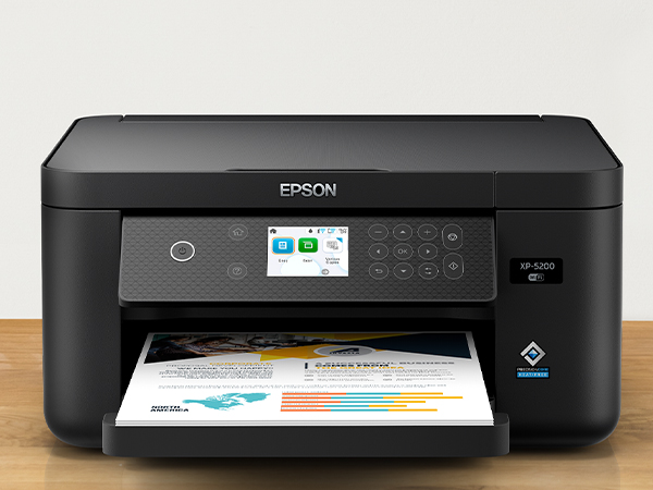 Stack of colorful printed flyers and black Expression Home XP-5200 printer sitting on desk.