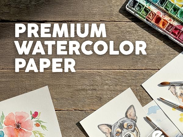 Text reads 'PREMIUM WATERCOLOR PAPER' with watercolor paint sets and supplies arranged on wooden surface.